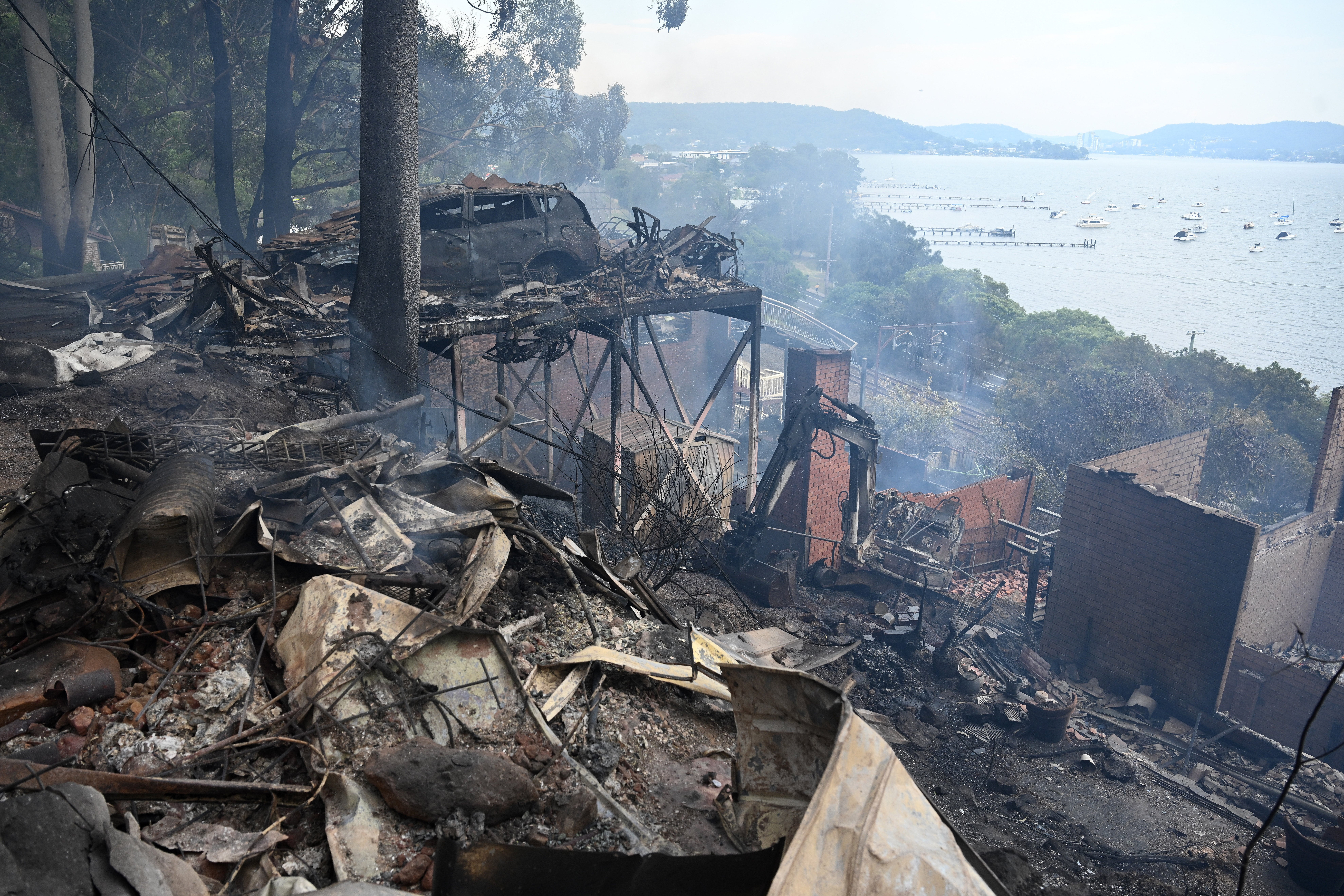 Ruins of buildings and a car smolder after a wildfire destroyed houses in Koolewong, Australia.