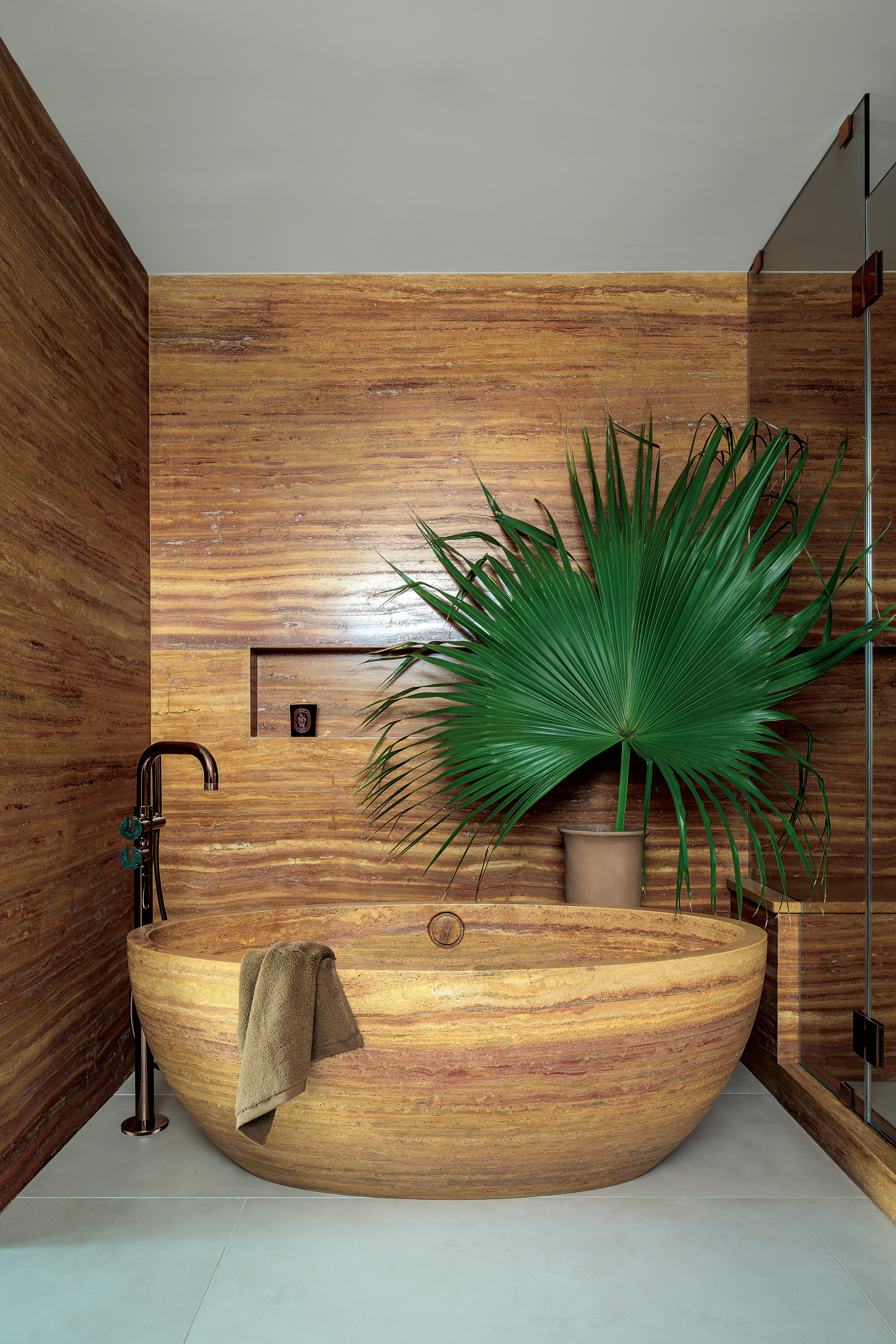 Bathroom with rich brown travertine walls and freestanding bath