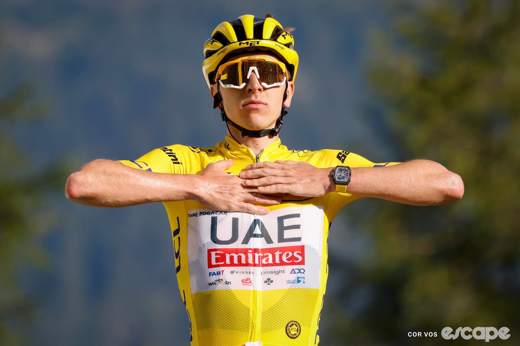 Tadej Pogacar celebrates a stage win in the yellow jersey at the Tour de France with both hands on his chest. His Richard Mille watch, with whom he has a financial arrangement, is visible..