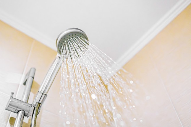 Shower head spraying water in bathroom for hygiene