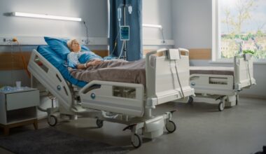 woman laying on hospital bed on an hospital room with an empty bed next to her.