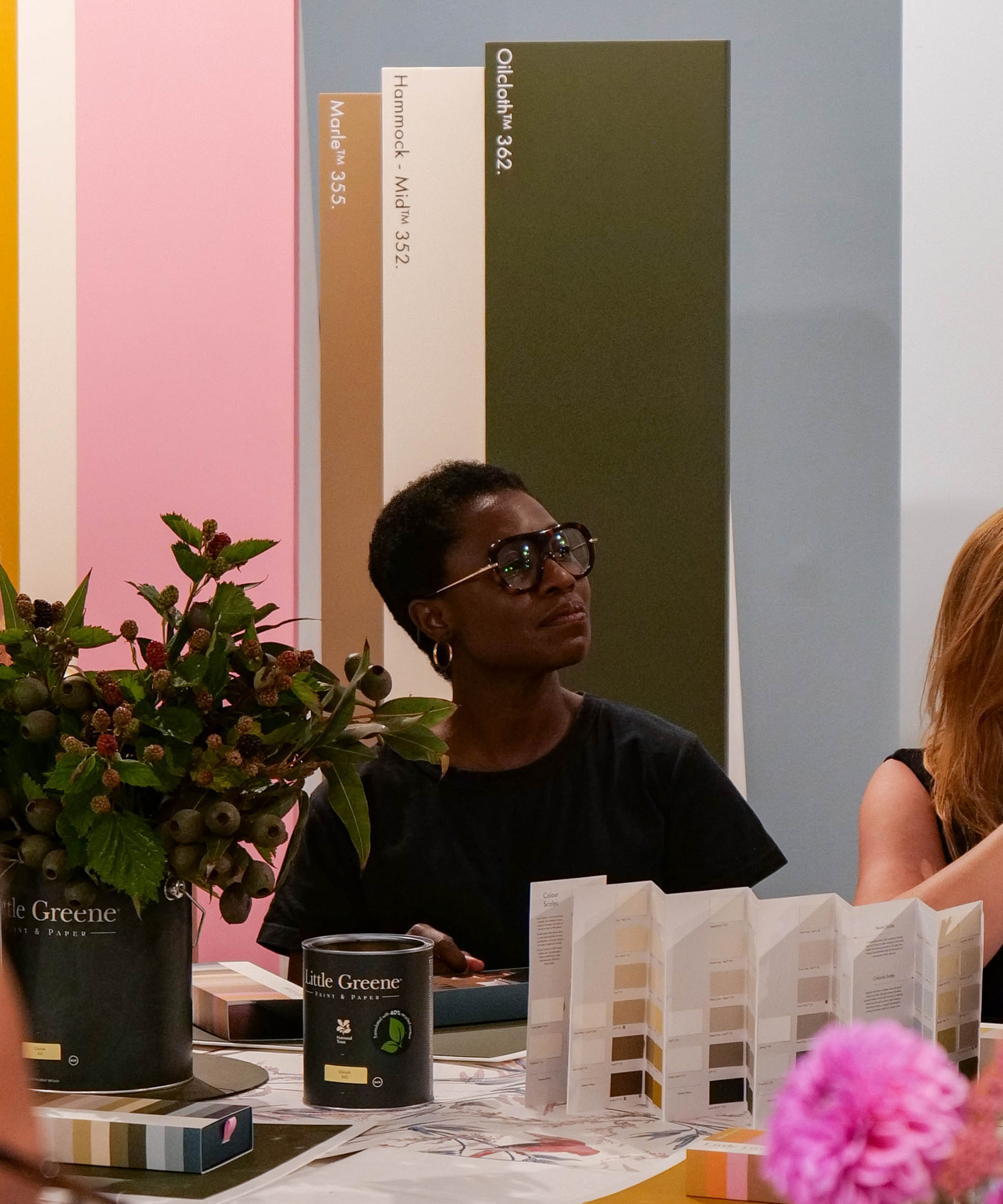 a woman sits in front of large boards displaying paint colors