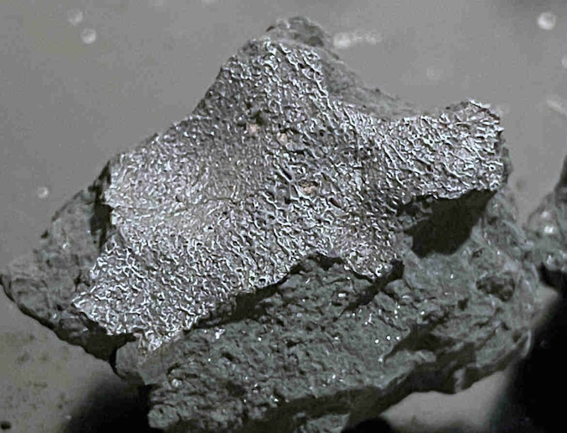 Meteorite strike of New Jersey home: Gray chunk of rock that is more silvery on top, with a wrinkled texture.