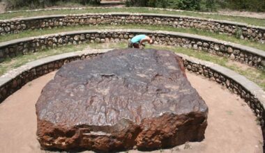 Large ancient stone in open-air archaeological site with tiered seating.