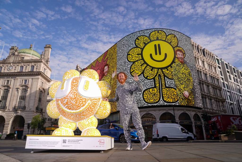 An artist stood next to a doodled sculpture in Piccadilly Circus