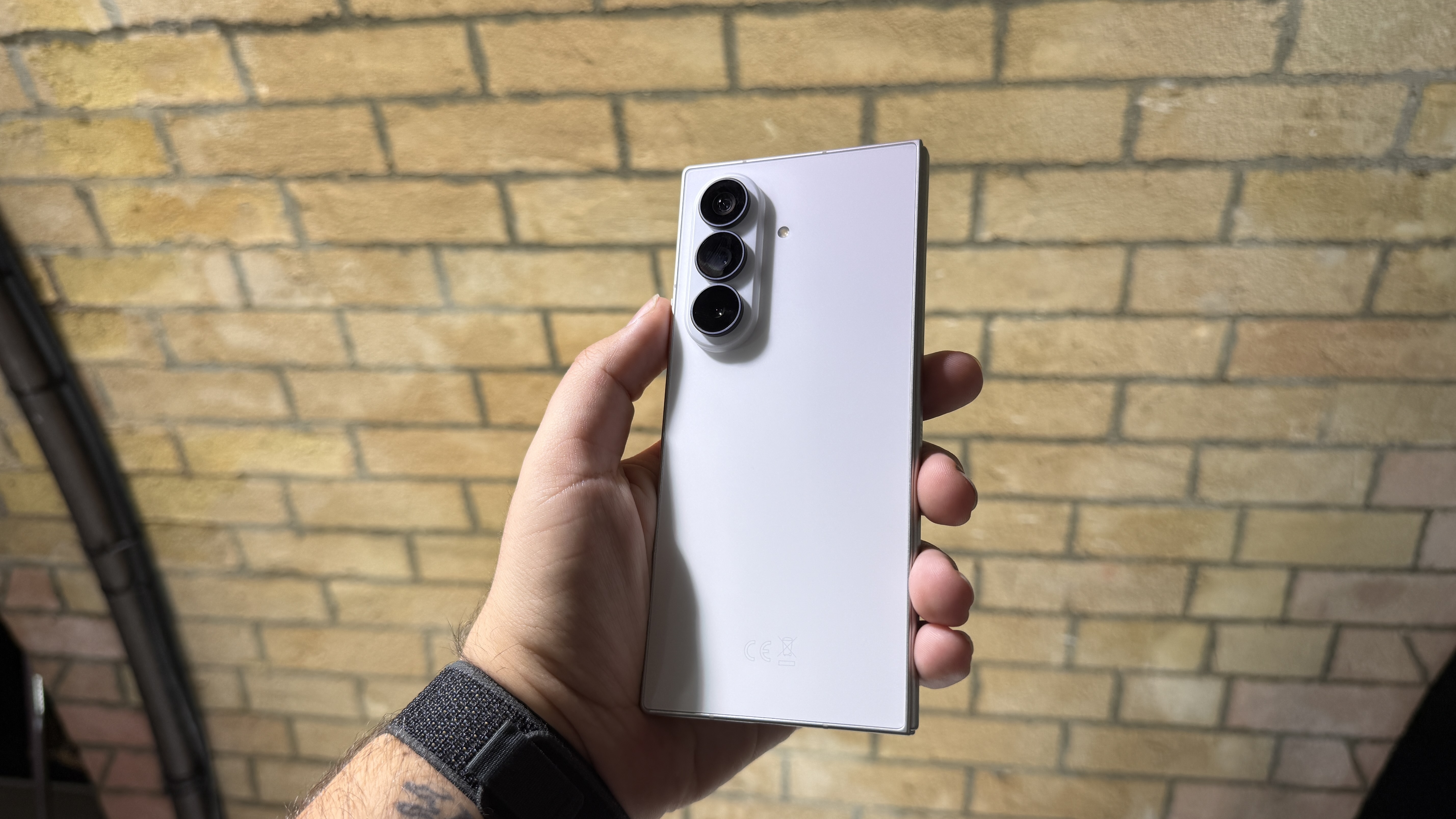 Samsung Galaxy Z Fold 8 and 8 Ultra in hand at a hands on event with a brick wall in the background