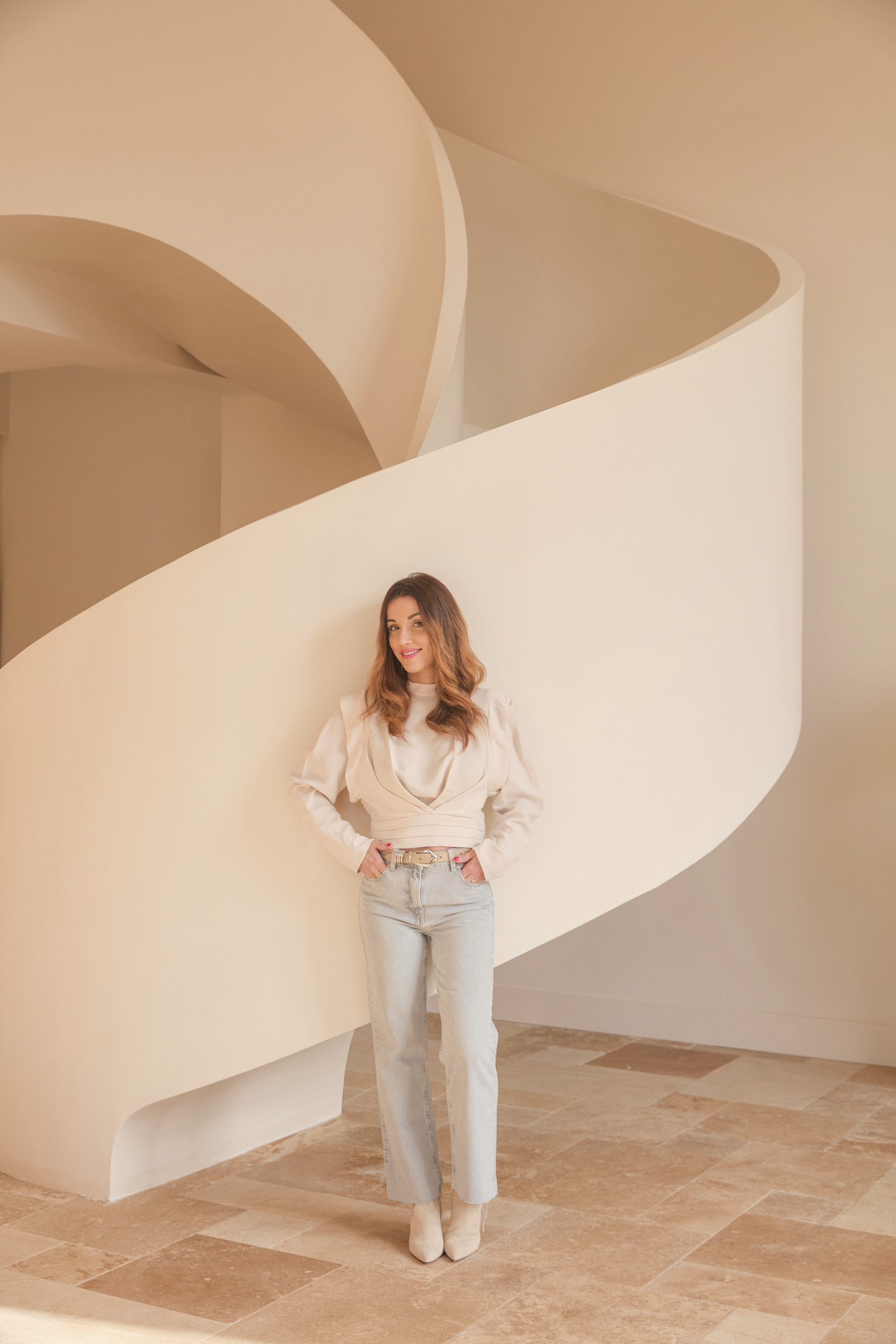 Interior designer H&eacute;l&eacute;na Monnet-Plat standing in front of a white spiral staircase