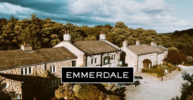 A view of the Emmerdale village with the Emmerdale logo in front of it.