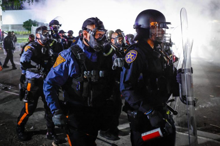 Police line up as tear gas spreads over protesters outside Delaney Hall, which is being used as an Immigration and Customs Enforcement (ICE) detention center, in Newark, New Jersey, on May 30, 2026. New Jersey state authorities announced on May 29 they were taking charge of security outside a US immigration detention center after clashes between ICE agents and protesters angered by conditions faced by detainees inside. Days of unrest have led to arrests as a tough stance by US President Donald Trump's administration on immigration policy continues to draws opposition, including from authorities in Democratic-led states. (Photo by kena betancur / AFP via Getty Images)
