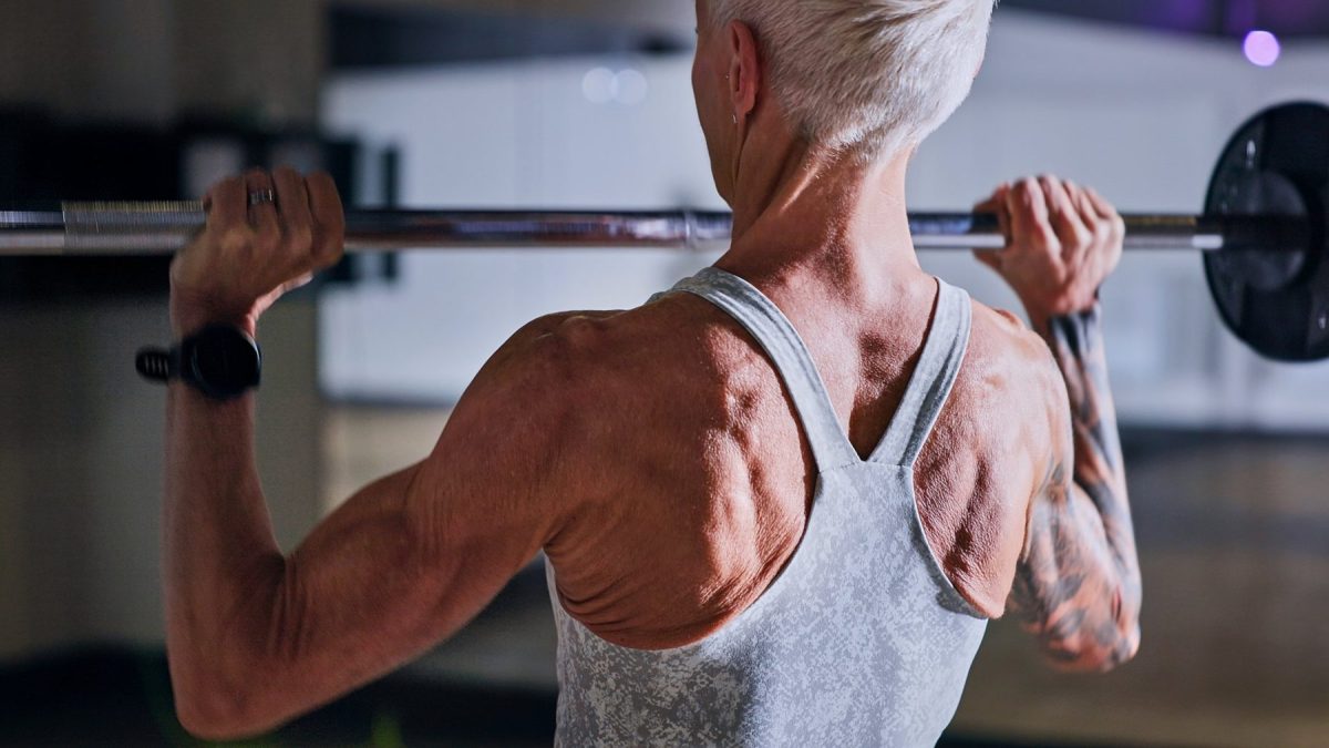 Fitness, bodybuilder and sports white woman weightlifting in a gym for a strong body. Exercise, health and training with a female athlete concentrating while lifting weights for a workout