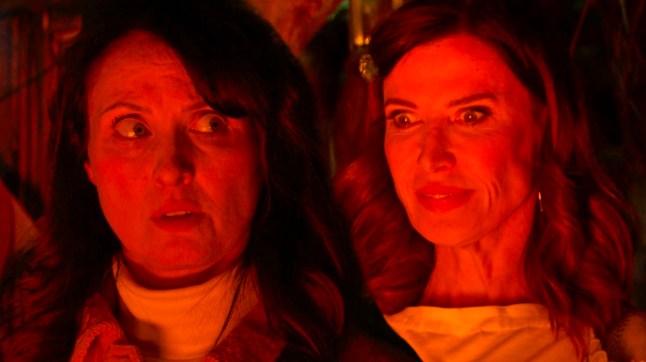 Honey looks spooked as Bea grins staring into the flames in EastEnders