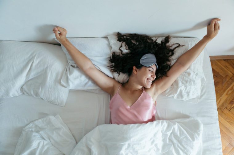 woman waking at the bright morning. sleeping mask white sheets
