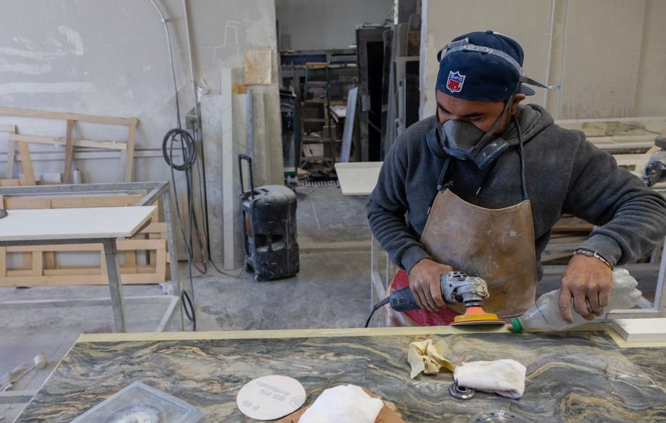 Sun Valley, CA - October 31: A stone countertop fabricator wears a mask to help protect against airborne particles which can contribute to silicosis at a shop on Tuesday, Oct. 31, 2023 in Sun Valley, CA. (Brian van der Brug / Los Angeles Times via Getty Images)