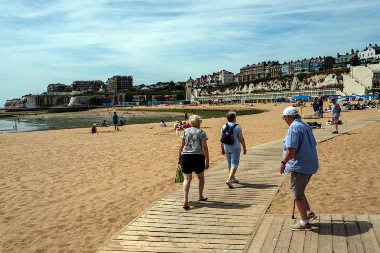 BROADSTAIRS, ENGLAND - JULY 7: People walk on the beach on July 7, 2026 in Broadstairs, England. Britain's Health Security Agency has issued yellow heat health alerts for the Midlands, eastern and southern England through to 12 July as temperatures are forecast to build into heatwave conditions. For some regions affected, the hot spell could mark the third official heatwave of the season, following record-breaking temperatures in May and June. (Photo by Carl Court/Getty Images)