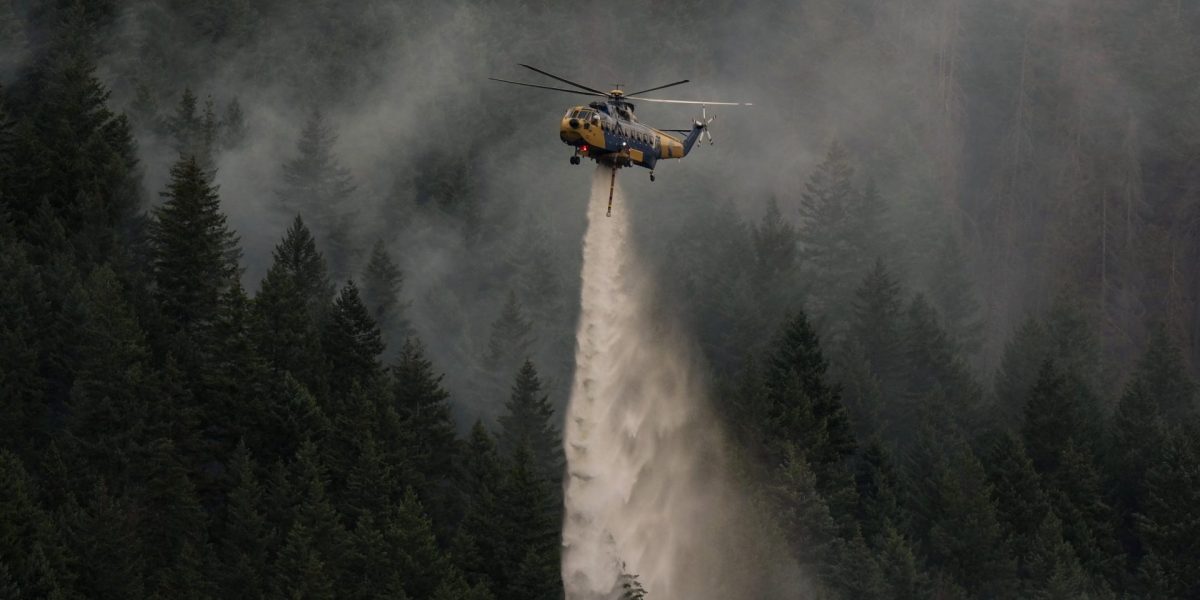 A helicopter drops water while fighting the Brunswick Creek wildfire in Boston Bar, British Columbia, on Thursday, July 9, 2026. (Darryl Dyck/The Canadian Press via AP)