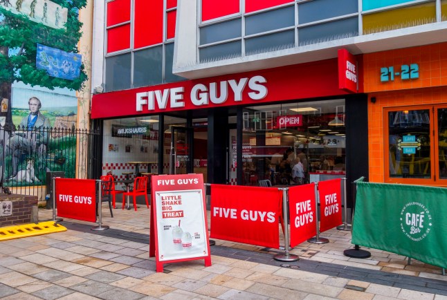 A branch of the restaurant chain Five Guys in the Market Square, next to the Victorian parish pump and mural of Charles Darwin in Bromley, Kent (South East London). Five Guys specialise in burgers, hot dogs, BLTs, fries and steaks.