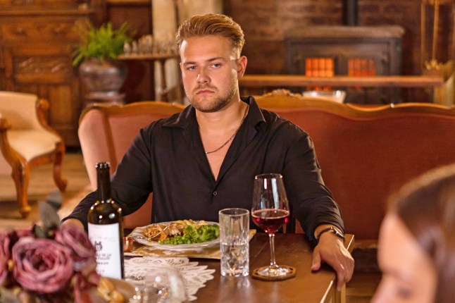 Matthew James Bailey as Ethan William in Hollyoaks, he looks upset while sitting at a dinner table in Rafe's mansion (Picture: Lime Pictures)