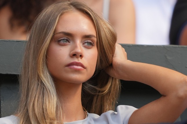 Laila Hasanovic girlfriend of Jannik Sinner of Italy watches as he plant against Alexander Zverev of Germany in the men's singles final at Wimbledon Tennis Championships in London. Wearing grey/white outfit and brushing hair back behind shoulder.