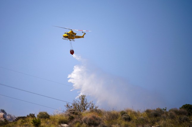 A helicopter releases water above a deadly wildfire near Almocaizar, Almeria, Spain, July 12, 2026. REUTERS/Ana Beltran