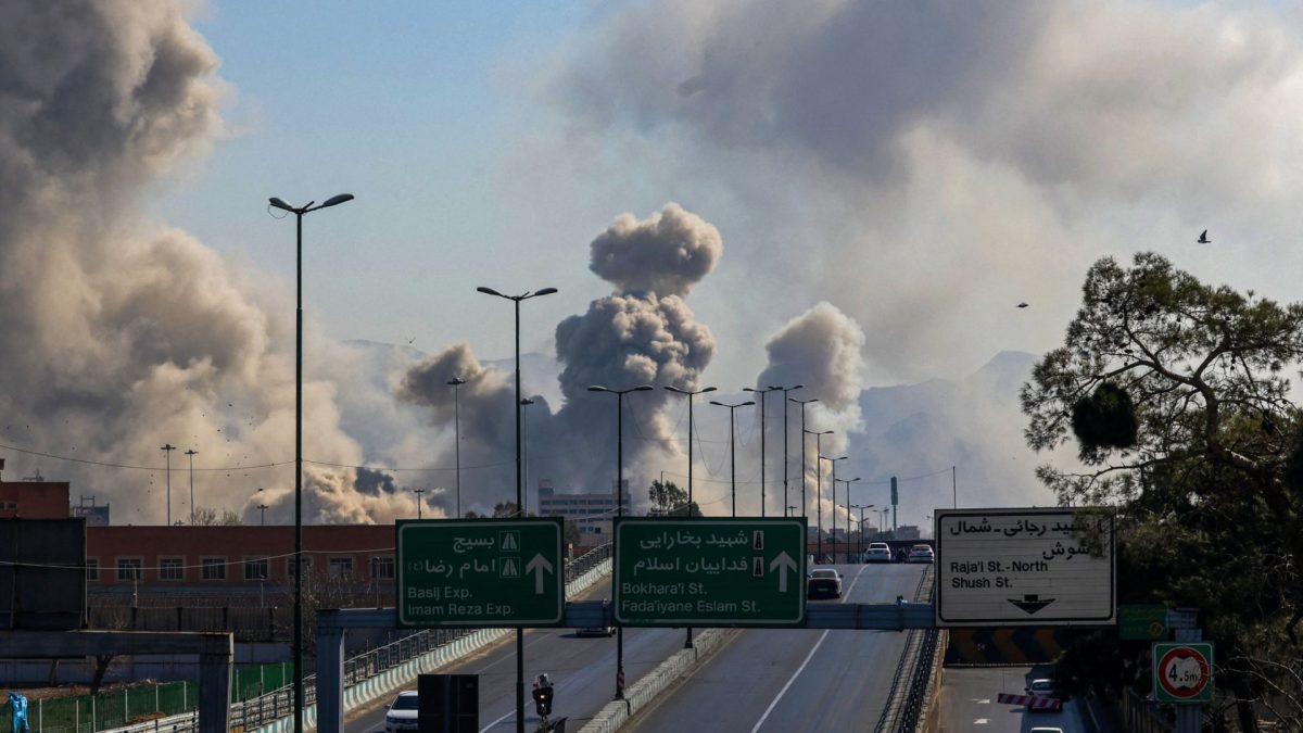 TOPSHOT - Motorists drive along an expressway as plumes of smoke rise after a strike in Tehran on March 5, 2026. Israel pounded Tehran with fresh strikes and Iran targeted Kurdish guerilla groups in Iraq on March 5 as a spiralling war in the Middle East engulfed the entire region. (Photo by ATTA KENARE / AFP via Getty Images)