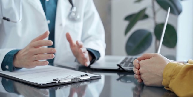 Doctor and patient consultation in clinic. Patient listens attentively as a doctor explains a diagnosis in a modern medical office, close up. Medicine and health care.