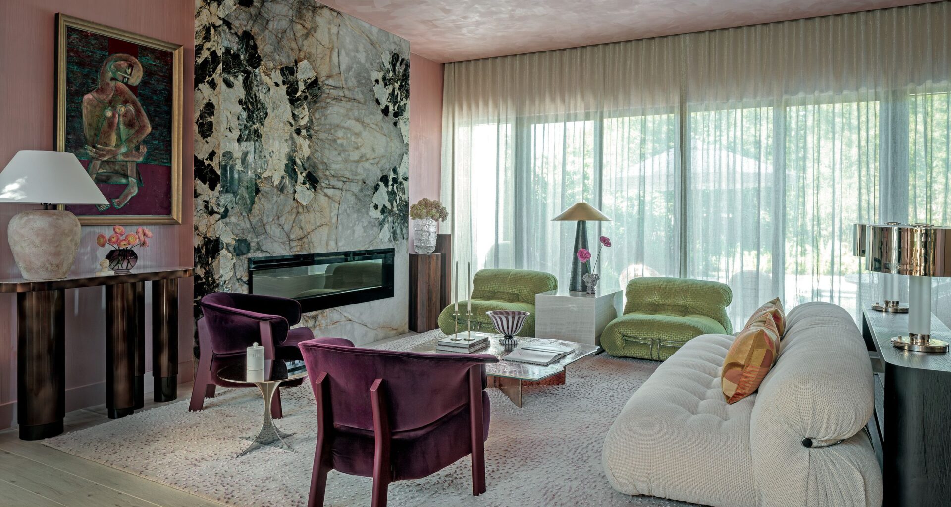 Living room with pink textured walls nad ceiling, green and white stone fireplace, white sofa, green armchairs and purple velvet armchairs