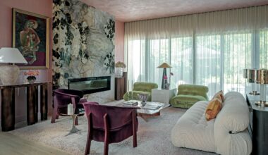 Living room with pink textured walls nad ceiling, green and white stone fireplace, white sofa, green armchairs and purple velvet armchairs