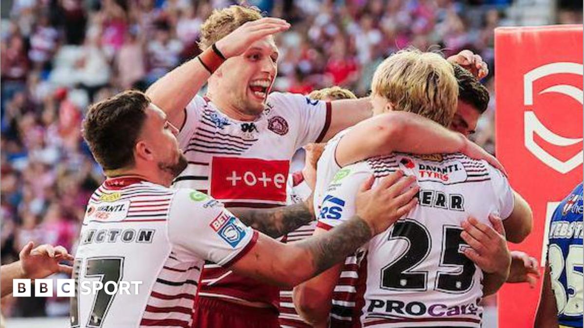 Wigan Warriors player Taylor Kerr, number 25 with his back to camera, is embraced and congratulated by team-mates after scoring a try.