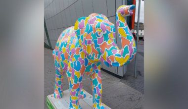 A colourful sculpture of an elephant with its trunk raised.