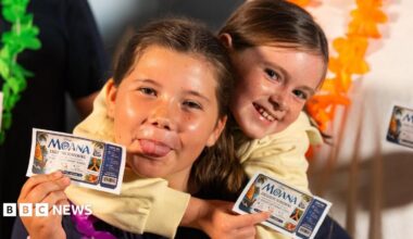 A close-up image of two girls holding 'Moana Exclusive Screening' cinema tickets.  One is poking her tongue out. They are both smiling and looking into the camera.