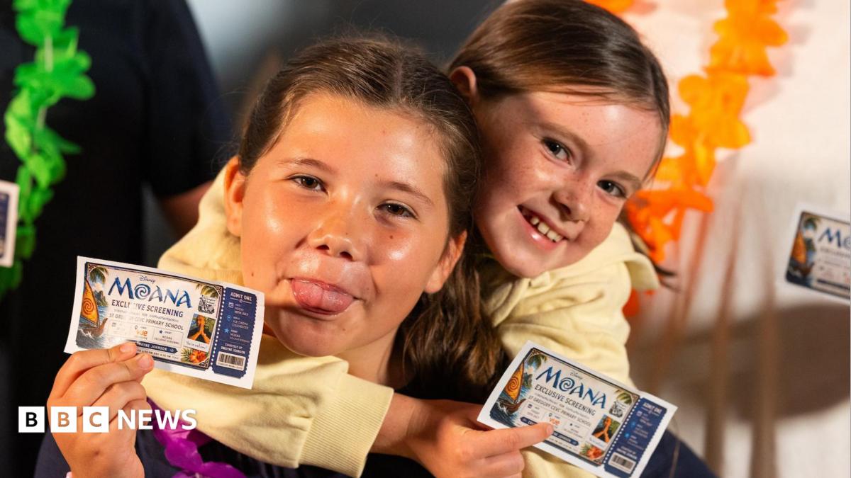A close-up image of two girls holding 'Moana Exclusive Screening' cinema tickets.  One is poking her tongue out. They are both smiling and looking into the camera.