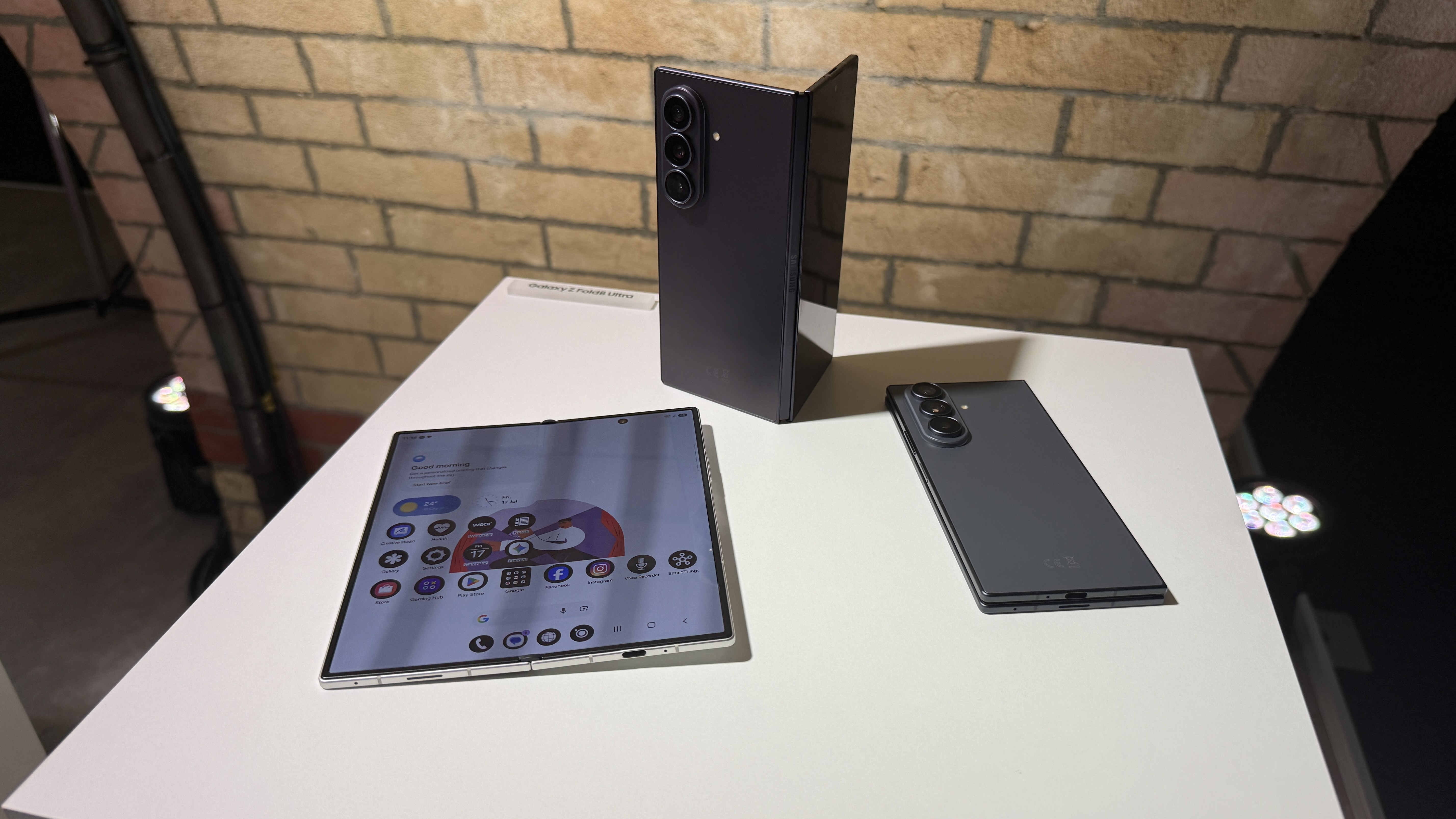 Samsung Galaxy Z Fold 8 and 8 Ultra in hand at a hands on event with a brick wall in the background