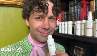 A man with curly hair wearing a green shirt and pink neck tie.