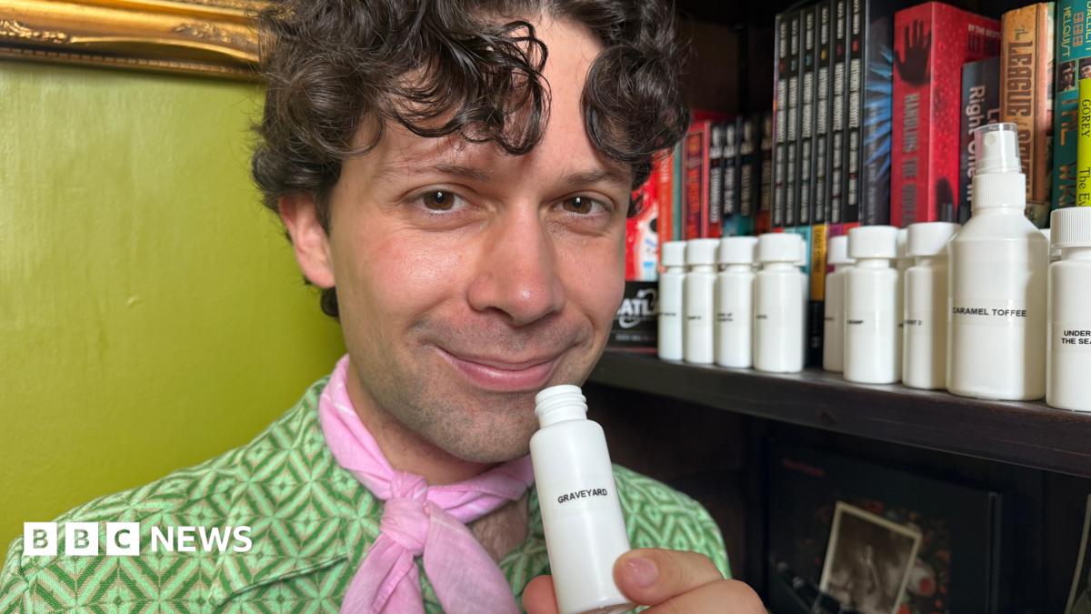 A man with curly hair wearing a green shirt and pink neck tie.