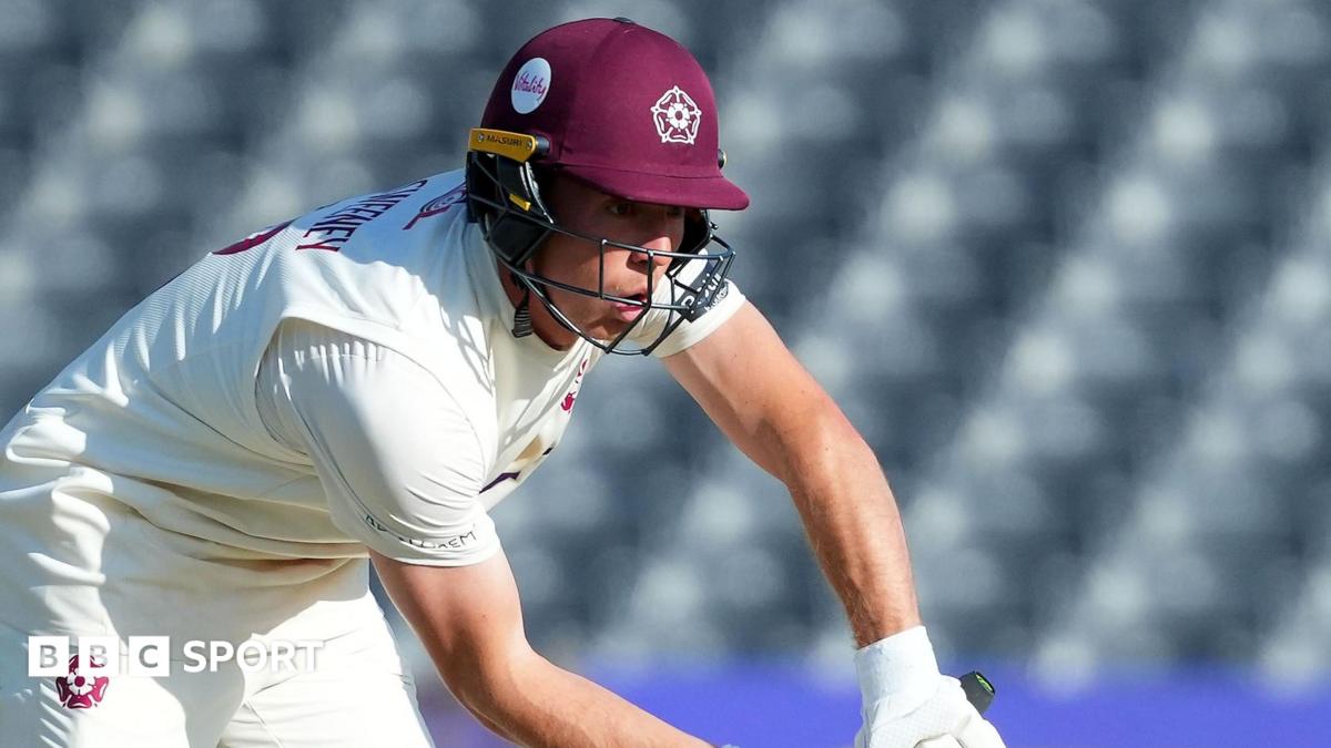 Nathan McSweeney in cricket whites and a claret Northants batting helmet defends the ball