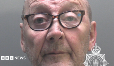 James Hughes police mugshot. He has stubble and is wearing spectacles