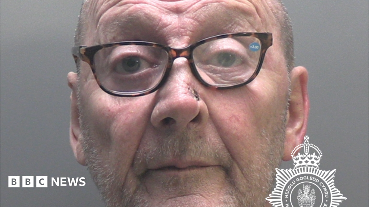 James Hughes police mugshot. He has stubble and is wearing spectacles