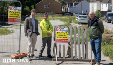 Residents stand beside anti-fly-tipping signs at the cleared Albert Road site near Sutton Station.