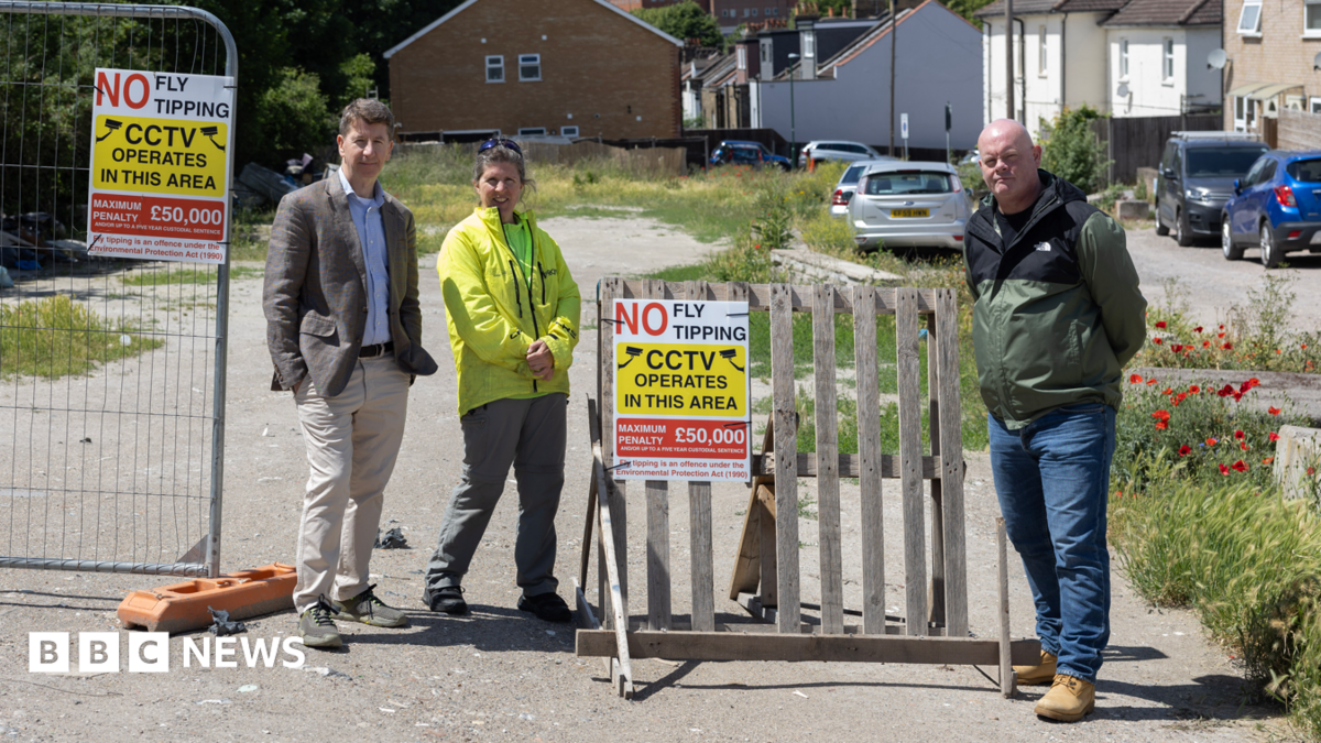 Residents stand beside anti-fly-tipping signs at the cleared Albert Road site near Sutton Station.