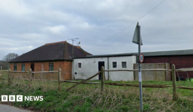 Derelict building in a field with a street sign in the foreground