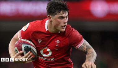 Louis Rees-Zammit playing in the red of Wales with ball under right arm