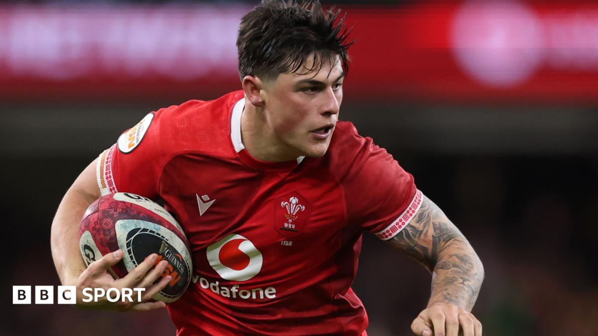 Louis Rees-Zammit playing in the red of Wales with ball under right arm