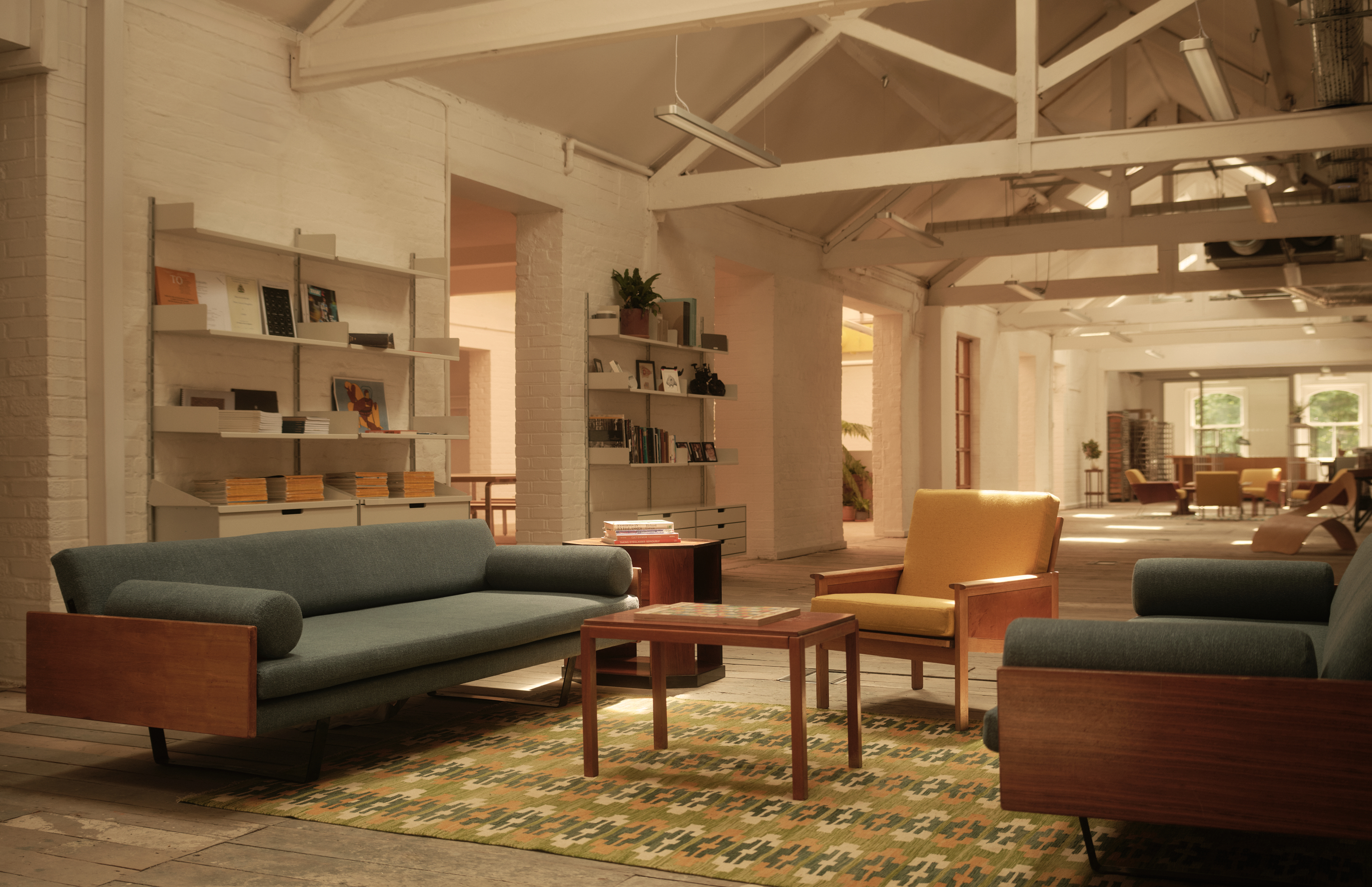 A warmly decorated former warehouse now filled with mid-century modern wooden furniture, colorful pops across floors and walls, statement lighting, glass blocks, and plants.