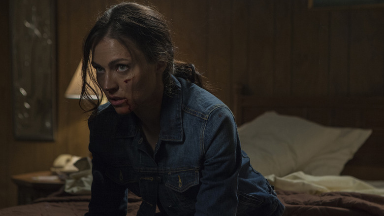 Ana sitting on a bed with a bloody face