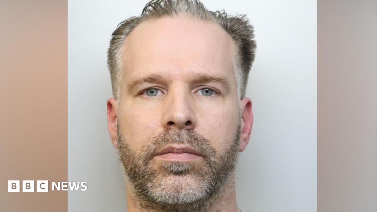 A custody image of Craig Hurcombe. He has stubble and a moustache, and a blank expression, looking at the camera