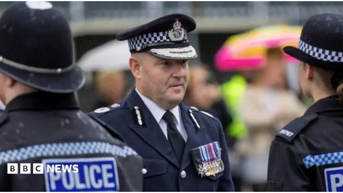 Craig Guildford, a man wearing ceremonial police uniform, looks at a line-up of police officers who are dressed in full police uniform.