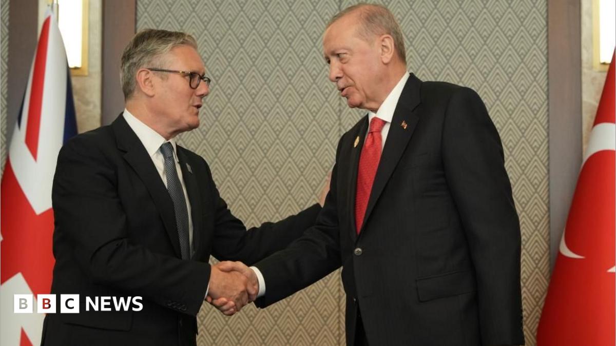 Sir Keir and Erdogan, both wearing dark suits, shake hands. Behind them are the Union Jack and Turkish national flag.