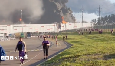 people walk away from a burning warehouse