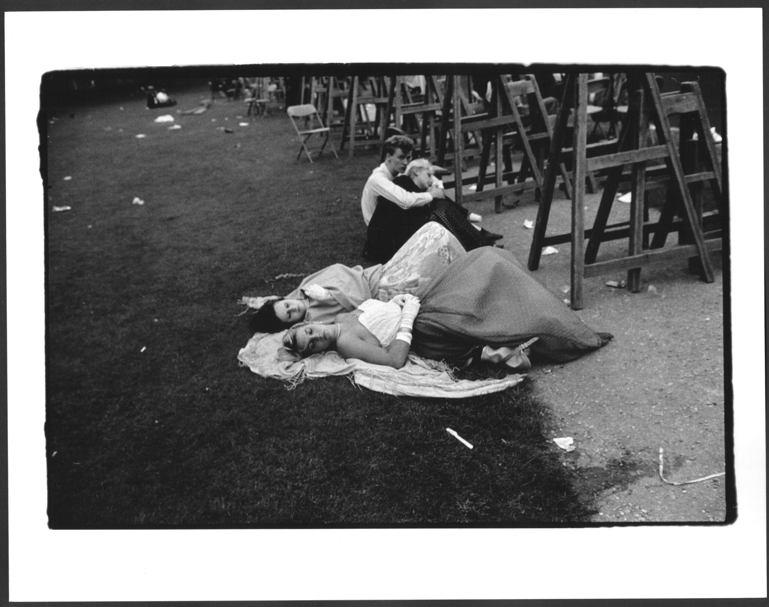 Girls in gowns sleep in the grass as the sun comes up at the Cambridge May Ball
