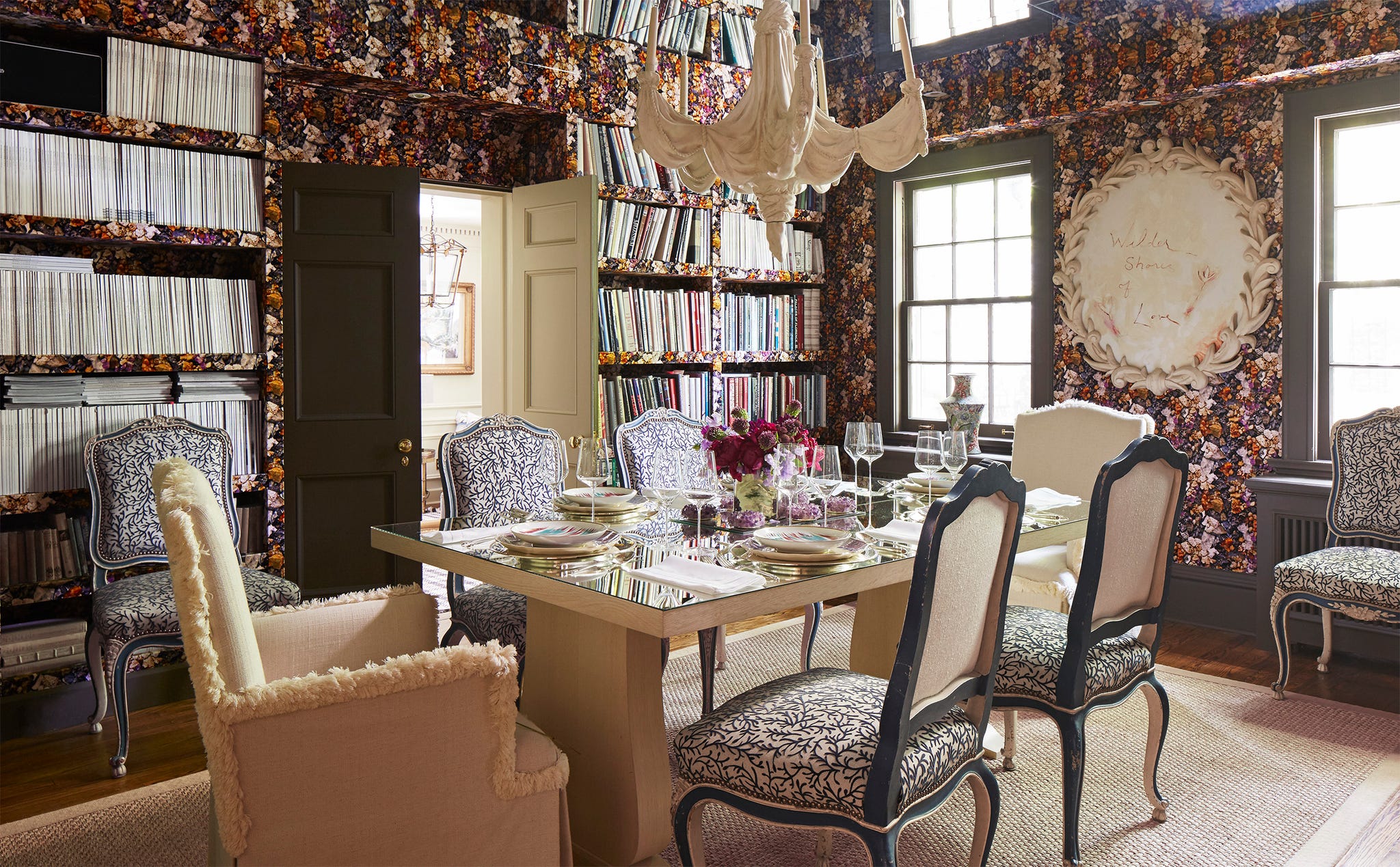 Elegant dining room featuring floral wallpaper, a mirrored table, ornate chairs, and decorative accents.
